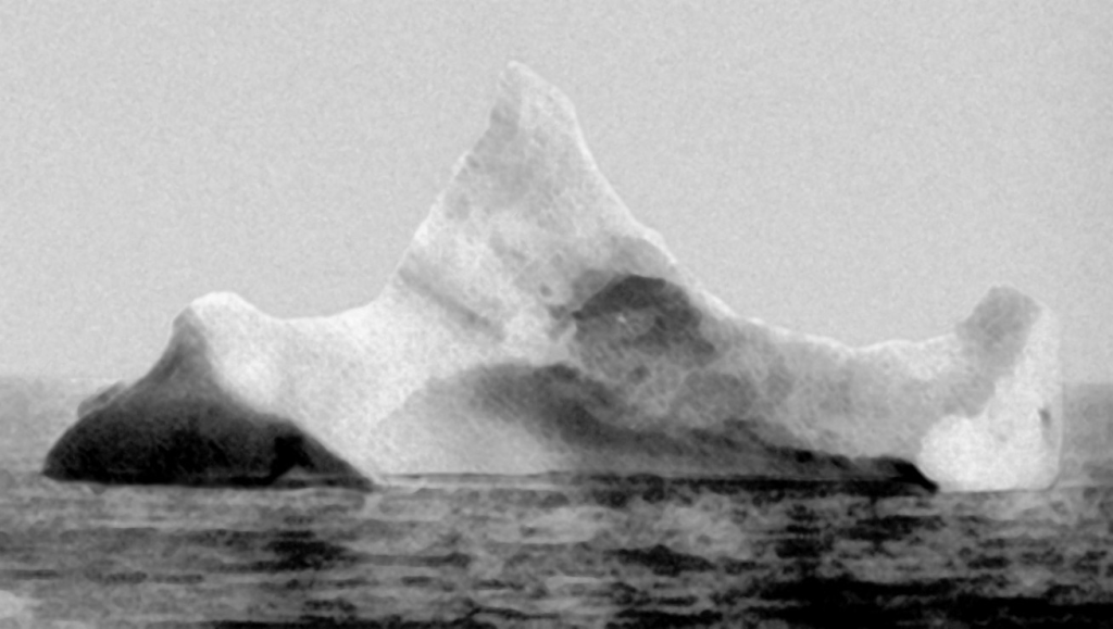 The iceberg thought to have been hit by Titanic, photographed on the morning of 15 April 1912. Note the dark spot just along the berg's waterline, which was described by onlookers as a smear of red paint.